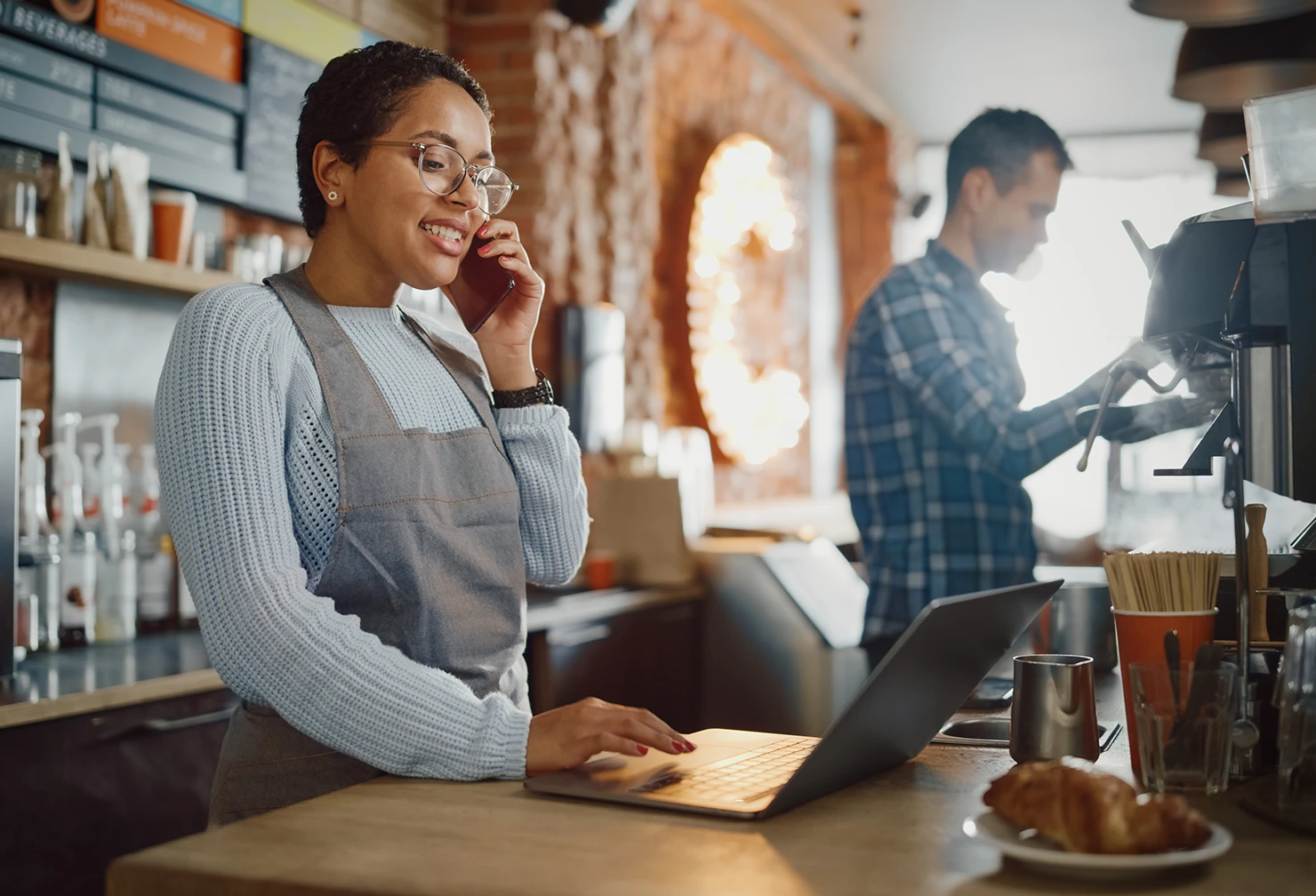 A female small business owner on the phone while working on her laptop