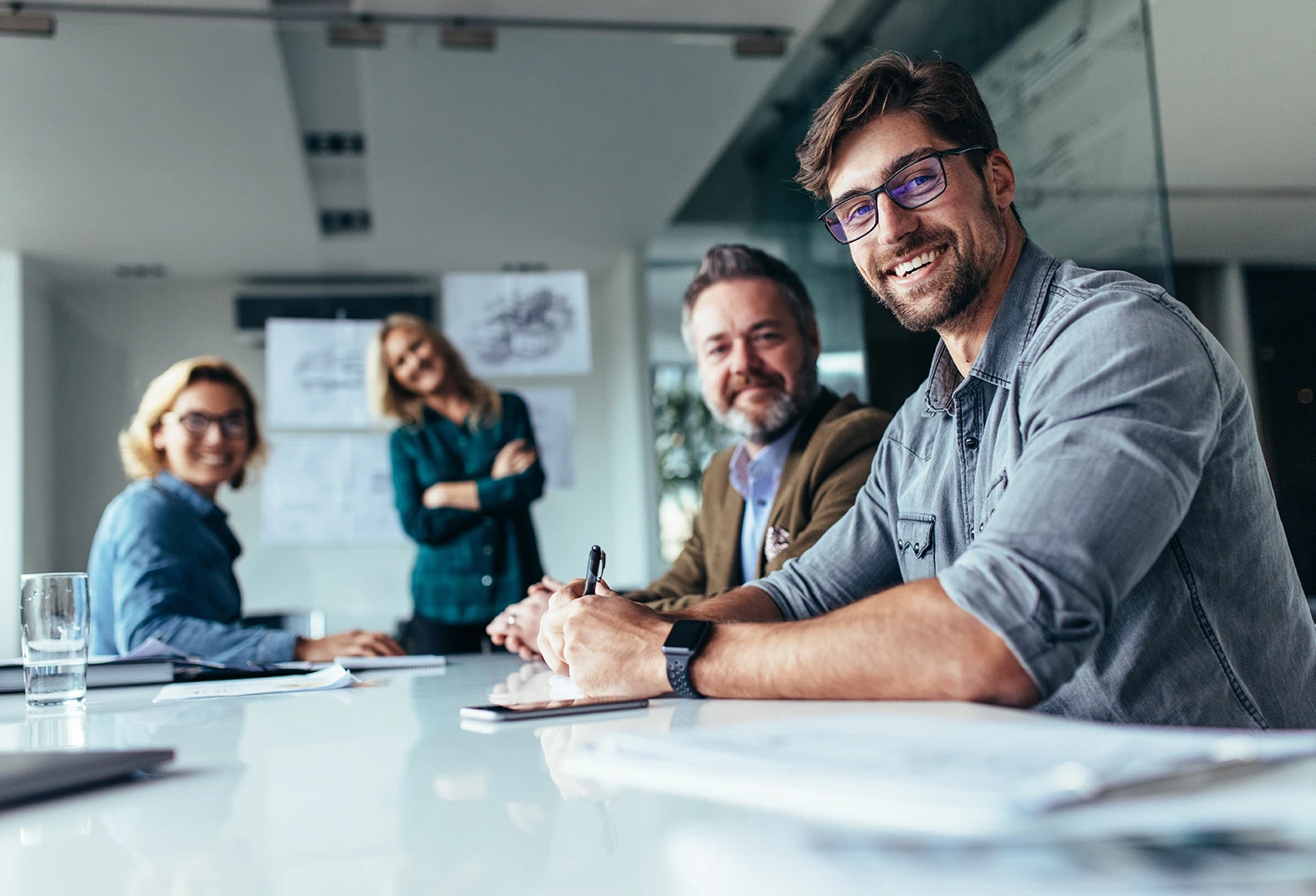 A group of people sitting around a boardroom table looking at the camera and smiling