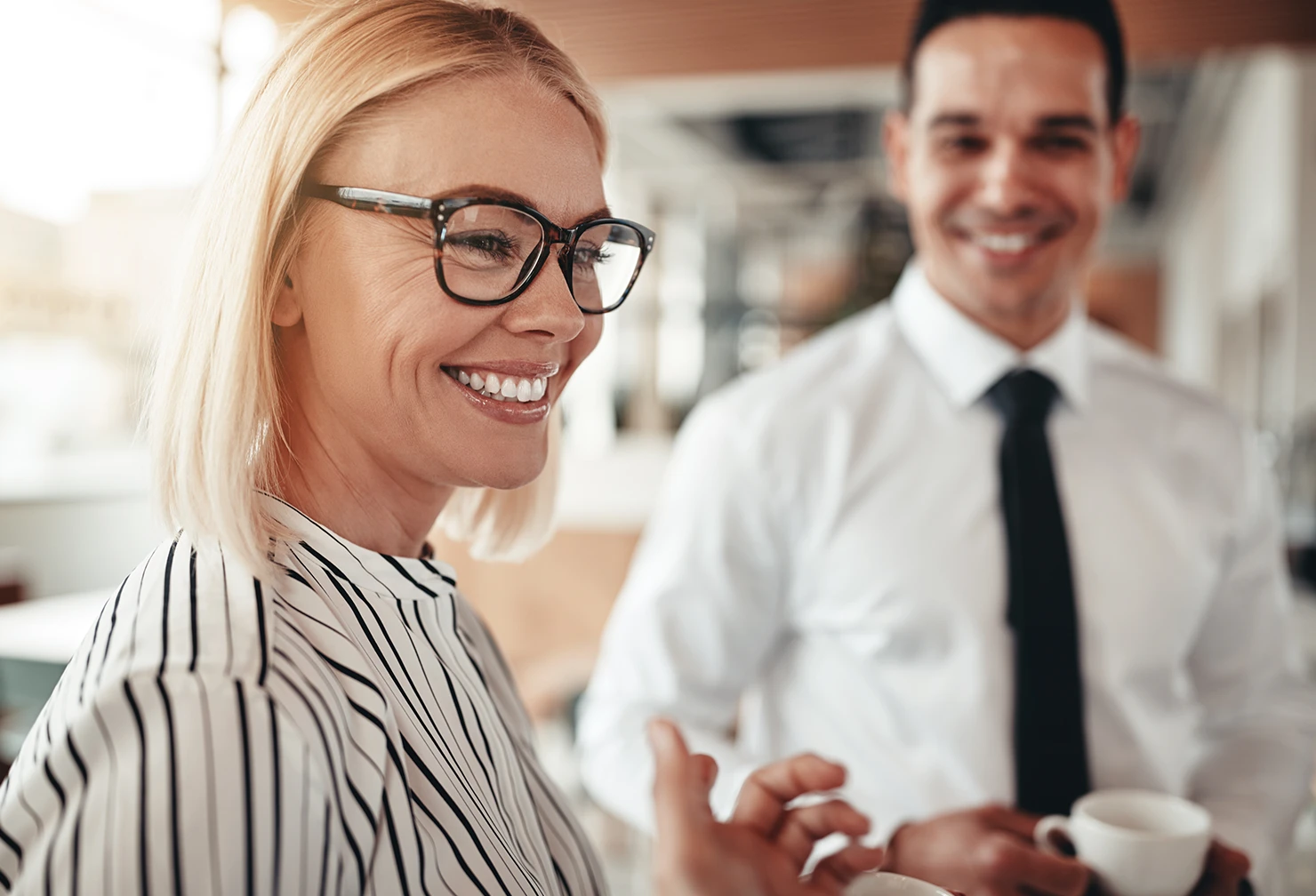 A corporate female business woman smiling while in discussion with a male colleague