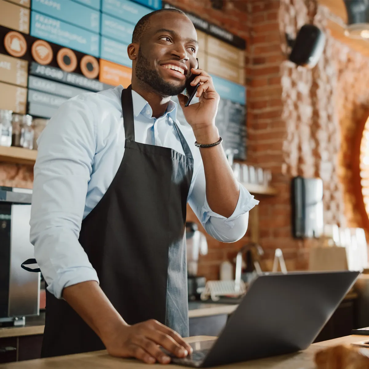 A male small business owner on the phone smiling
